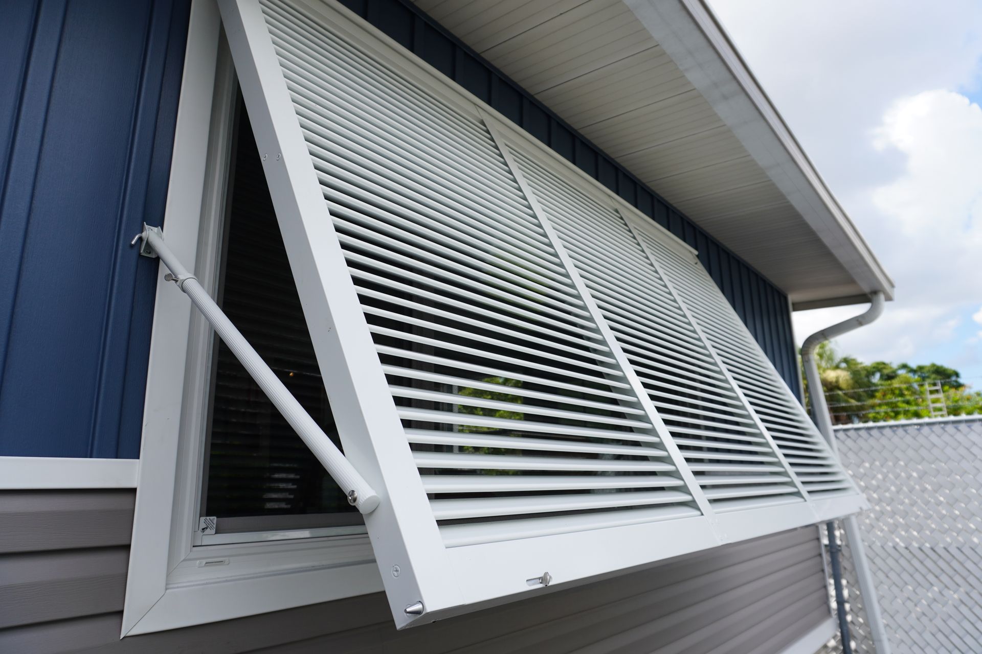 Open louvered window shutters on a blue house exterior