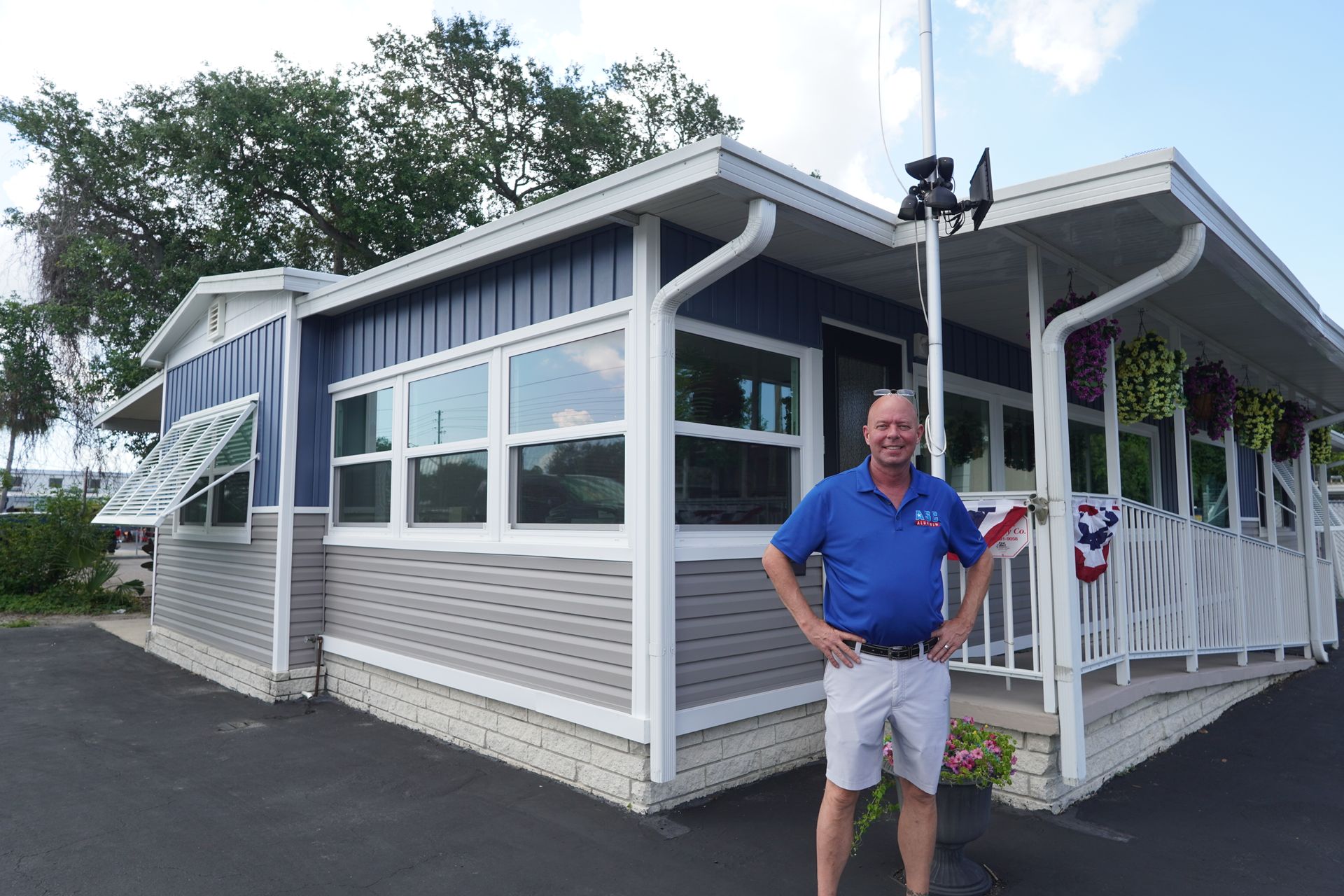 Man standing outside a white waterfront building with large windows and a wraparound porch