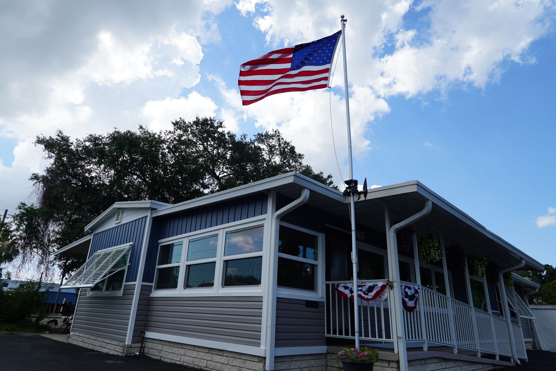 Small blue house with patriotic bunting and an American flag flying outside on a sunny day