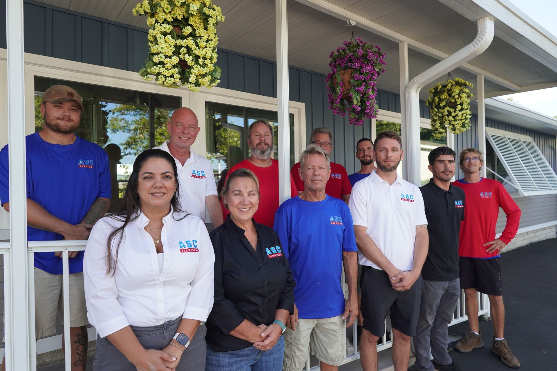 Group of employees standing outside a building in front of hanging flower baskets