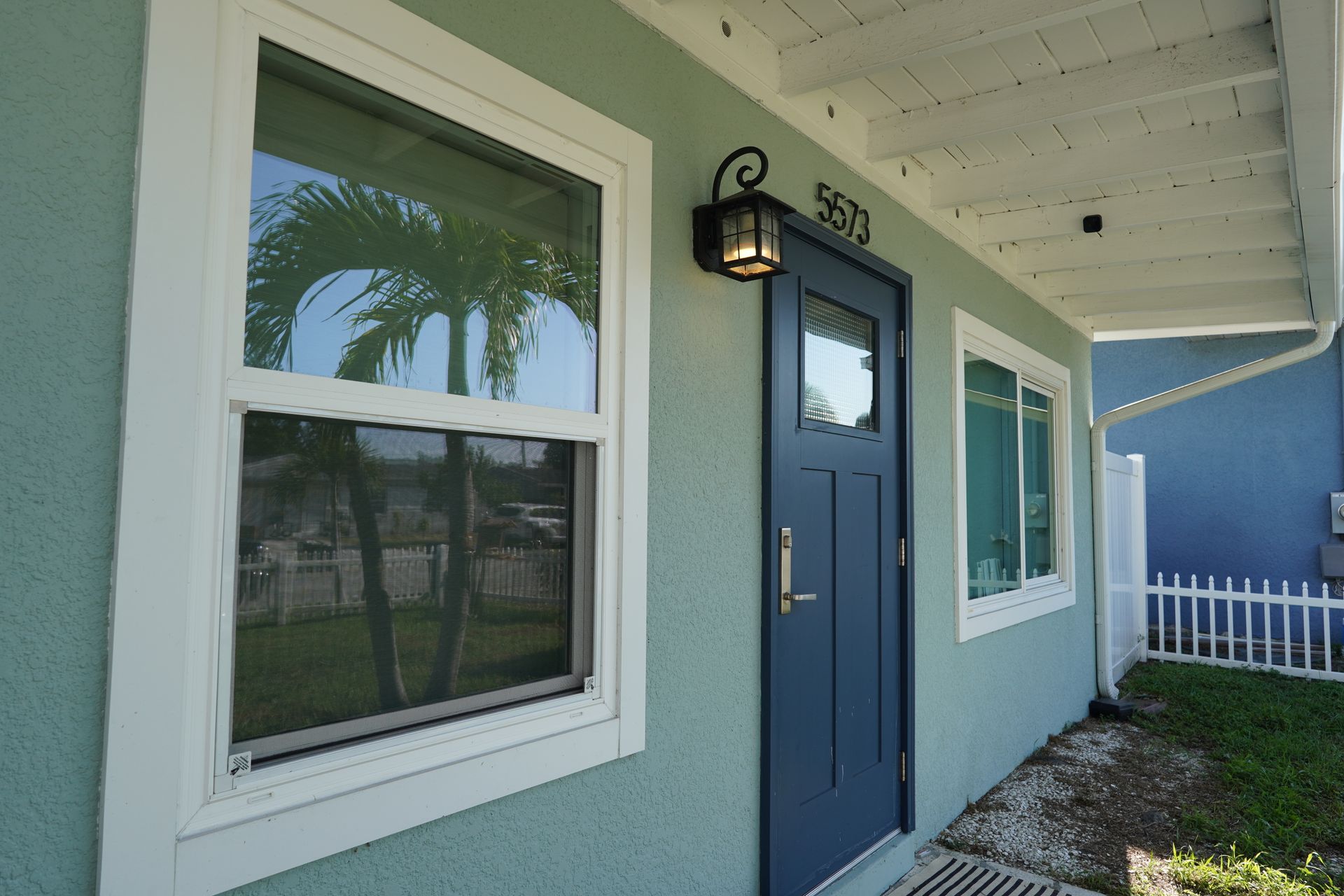 Blue door with wall lantern and windows on a light teal building exterior