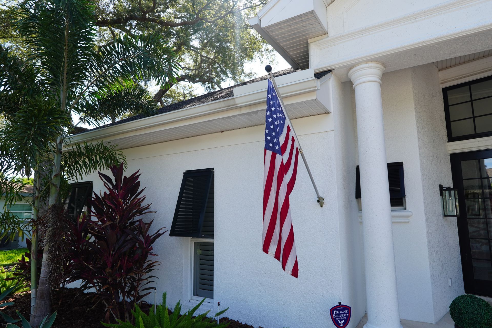 White house entrance with columns and an American flag hanging by the doorway.