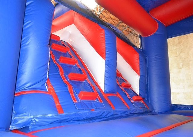 Blue, red, and white inflatable bounce house with climbing steps and a slide.