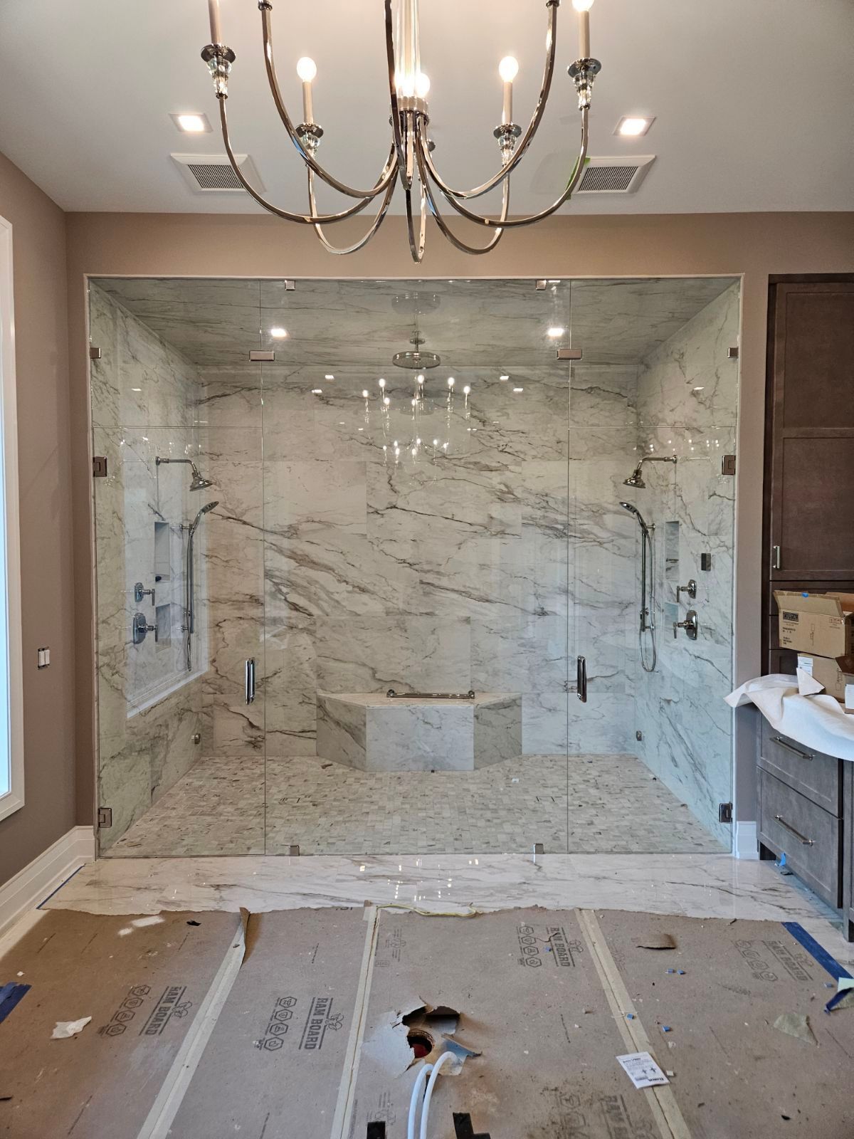 A bathroom with a walk in shower and a chandelier.