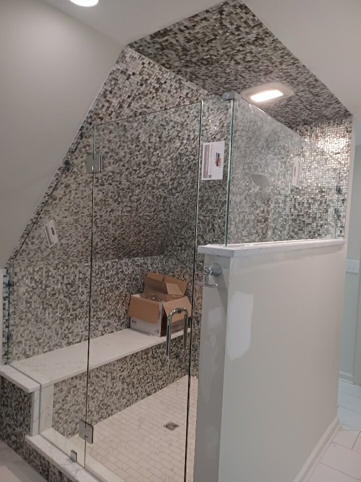 A bathroom with a walk in shower with a glass door.