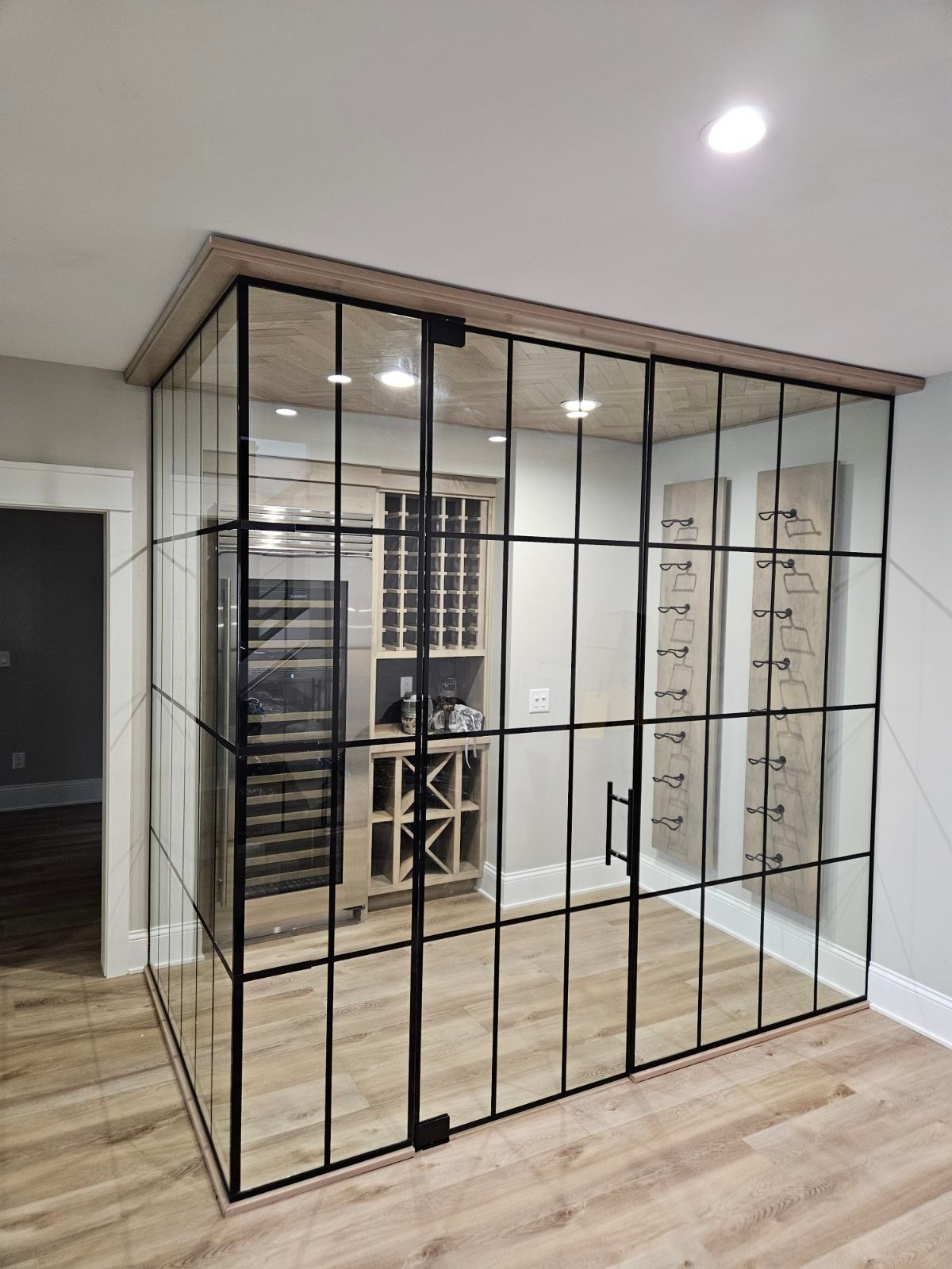 A wine cellar with a glass wall and sliding glass doors.