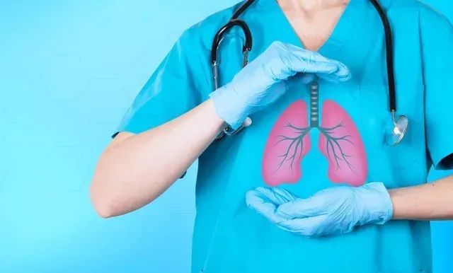 Medical professional holding a diagram of pink lungs, wearing blue scrubs and gloves.