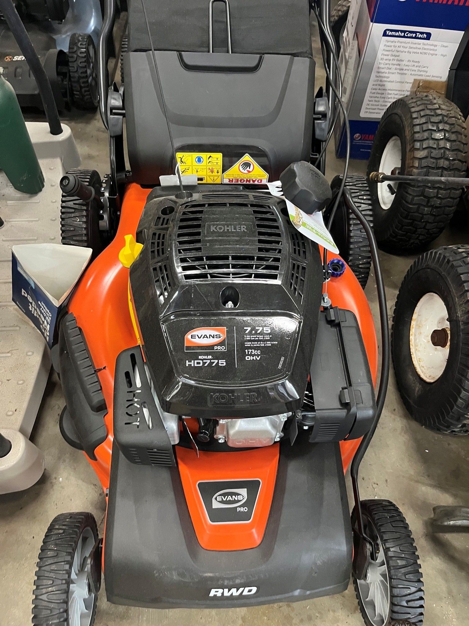 Red and black ride-on lawn mower parked indoors, front view, with large tires.