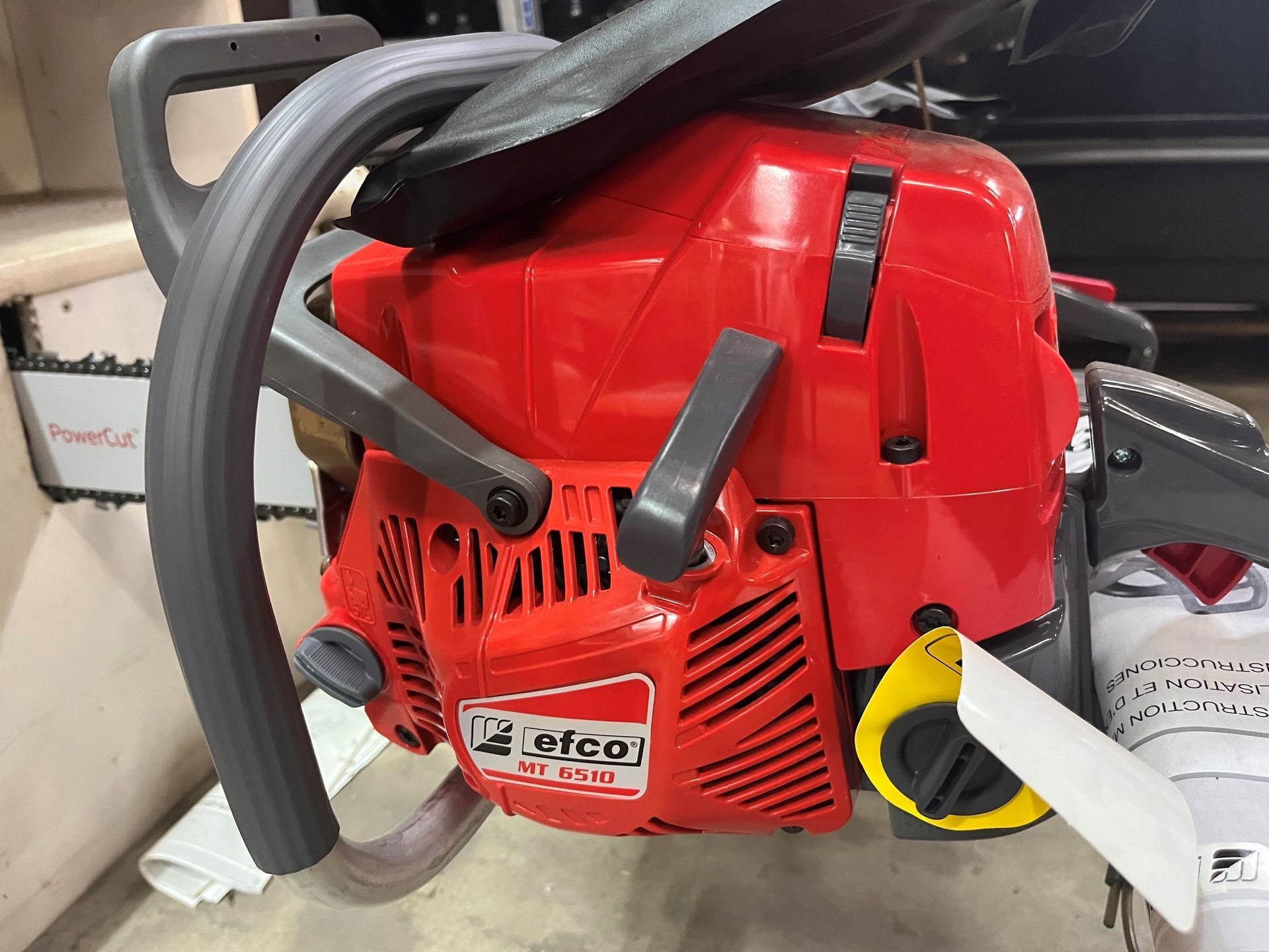 Red chainsaw with black handle and gray guard resting on a surface, close-up view.