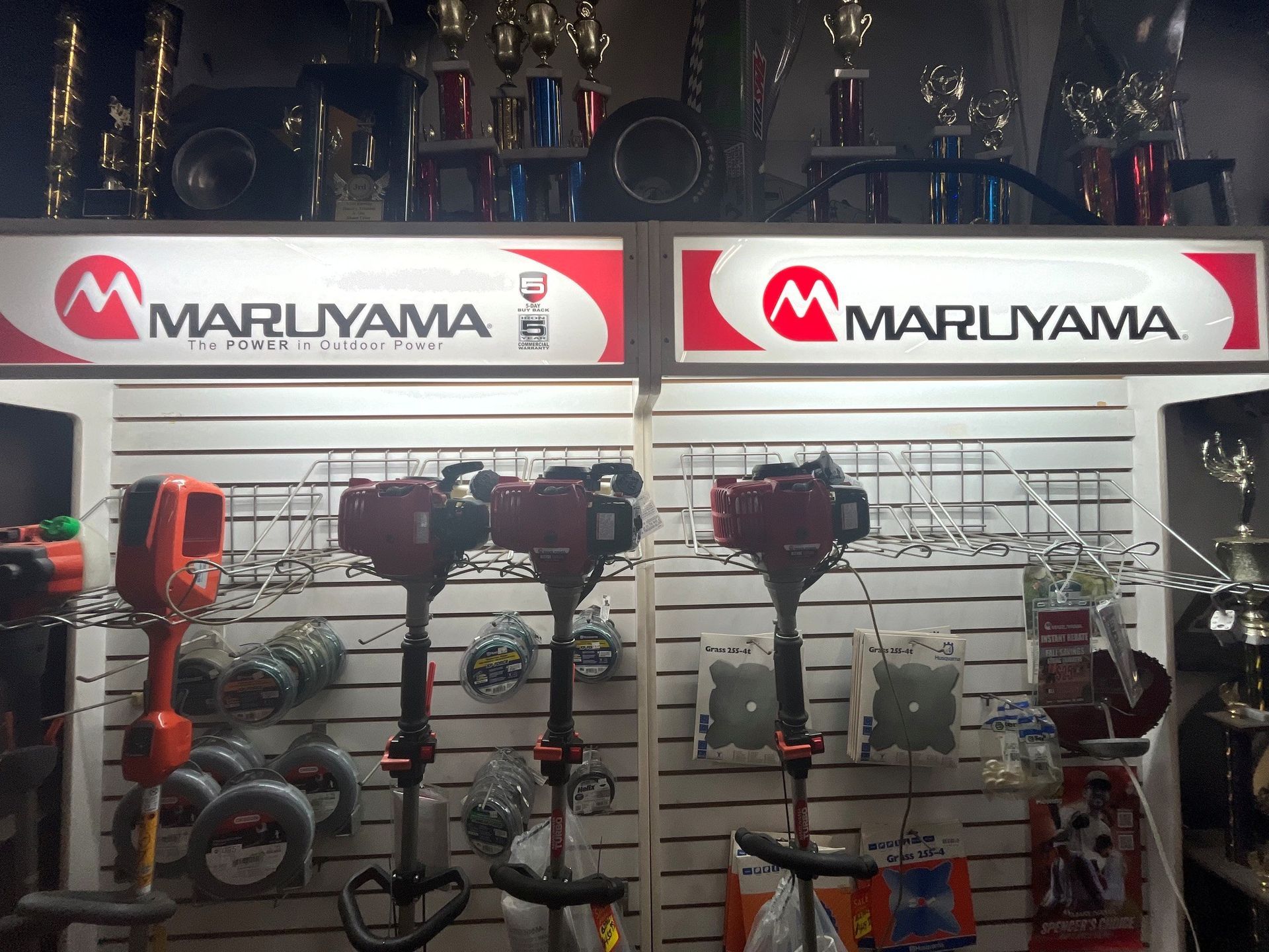 Maruyama display wall of red and black power tools in a store, with bright brand signs above.