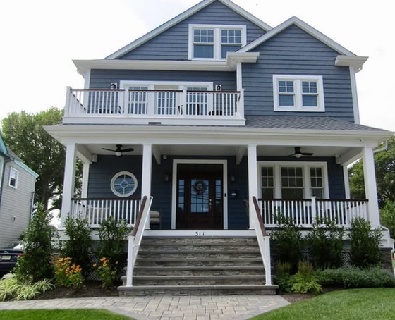 Blue house with white trim, porch, balcony, and steps leading to the front door.