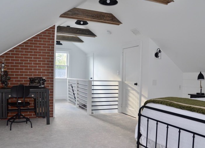 Loft bedroom with exposed beams, brick wall, and white railing