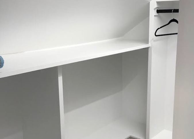 Empty white closet with shelves and a clothes hanger