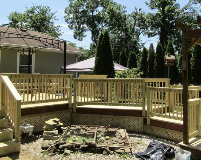 Newly built wooden deck in backyard with gazebo and trees