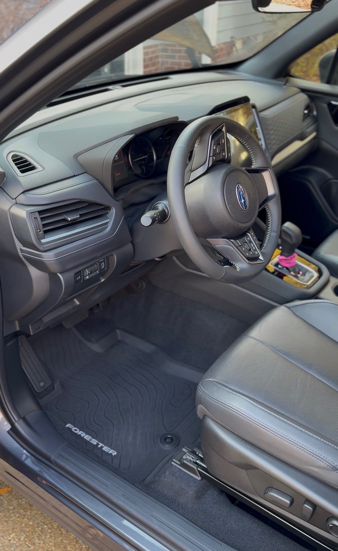 Interior of a Subaru Forester, black leather seats, steering wheel, dashboard, and floor mats.