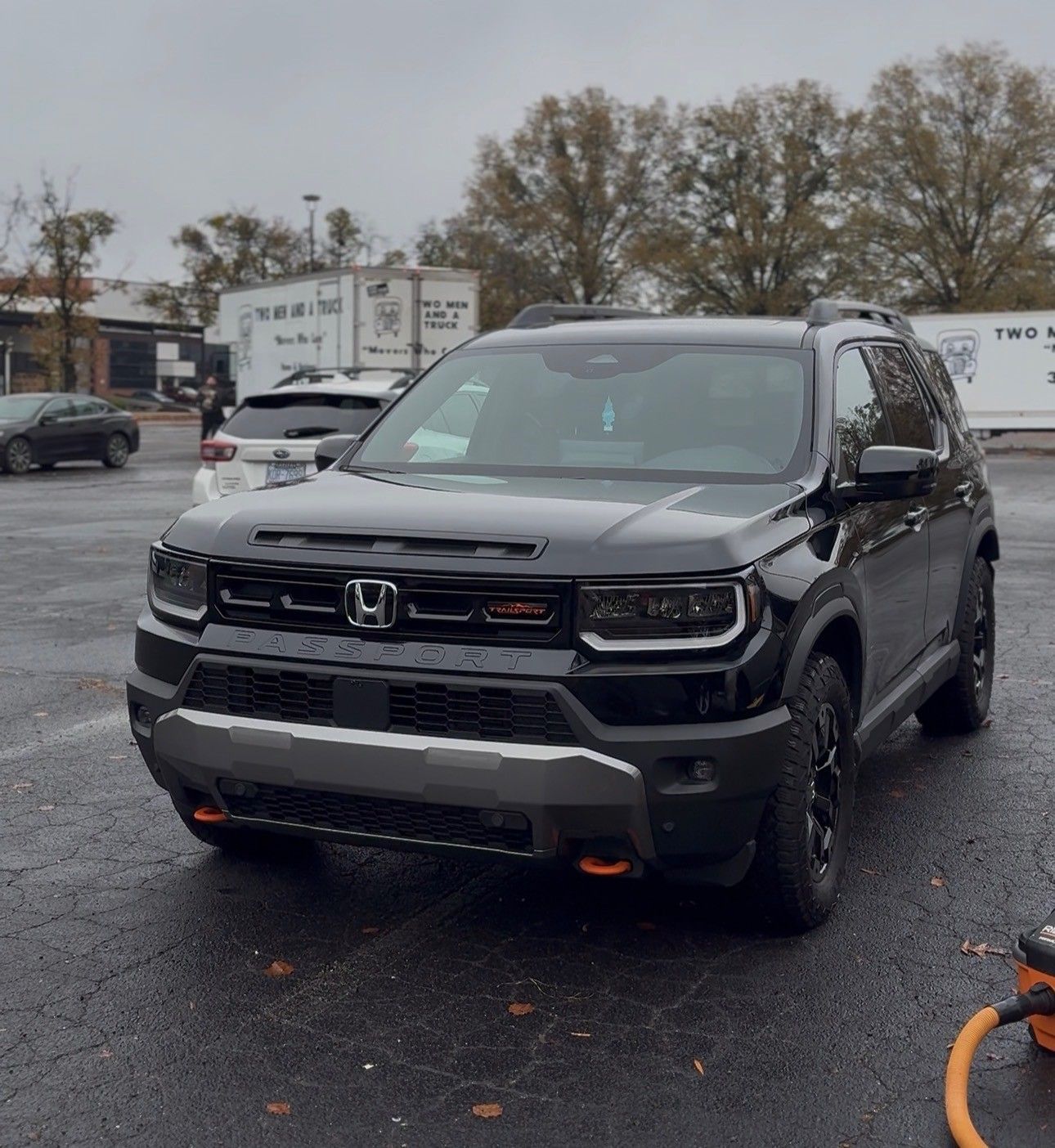 Black Honda SUV parked in a lot, overcast day. Orange accents on the front bumper.