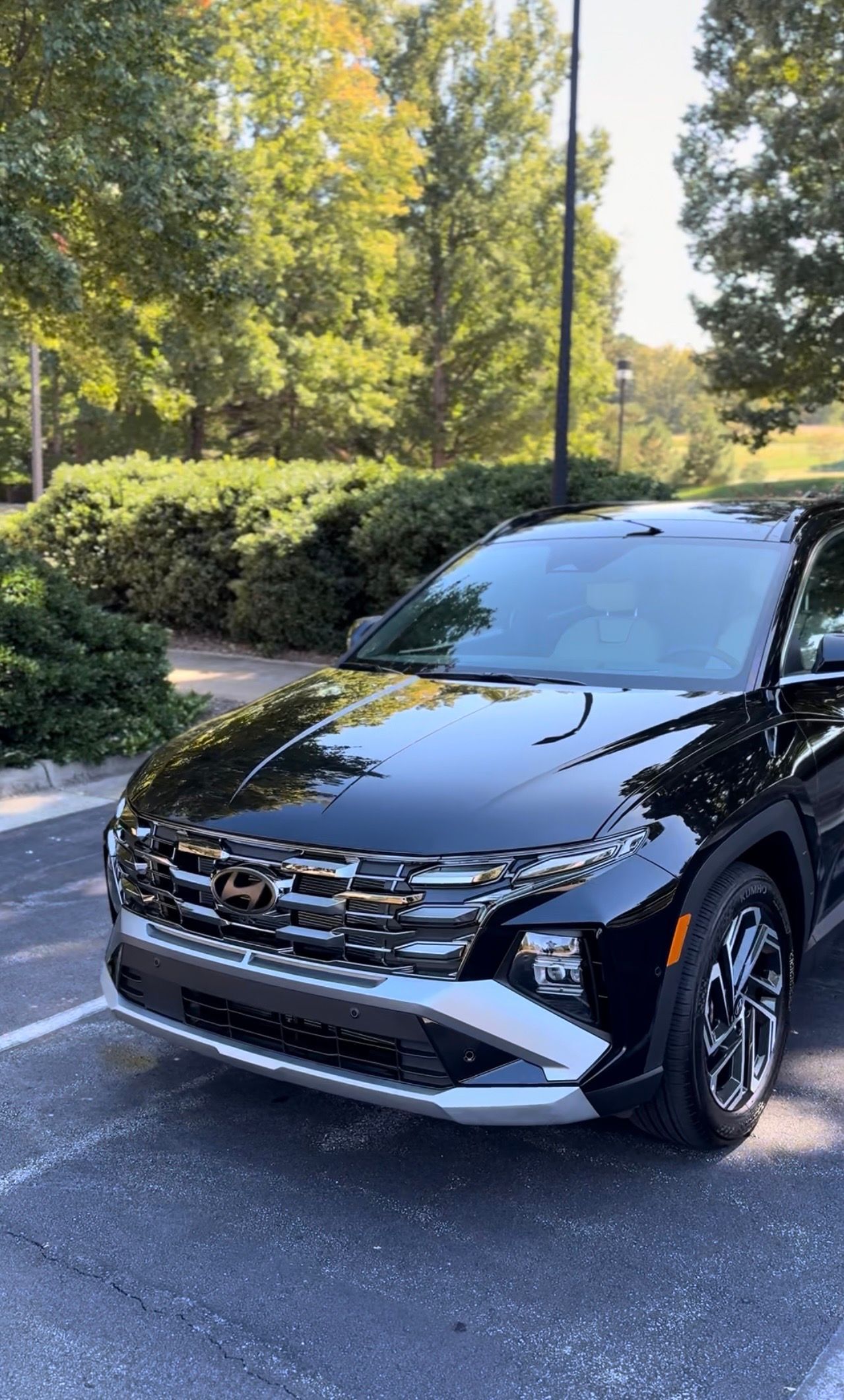 Black SUV parked on asphalt, trees in the background. Shiny chrome grille and trim.