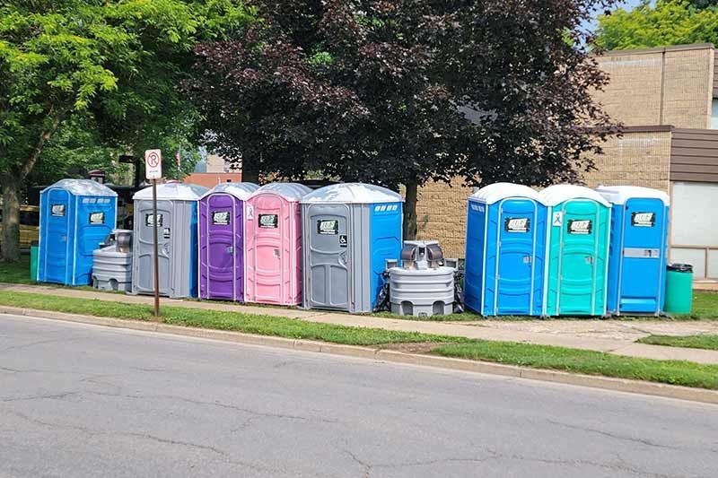 A row of portable toilets are lined up on the side of the road.