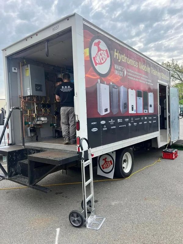 Mobile water heater display; two men work inside the truck. Trailer has 