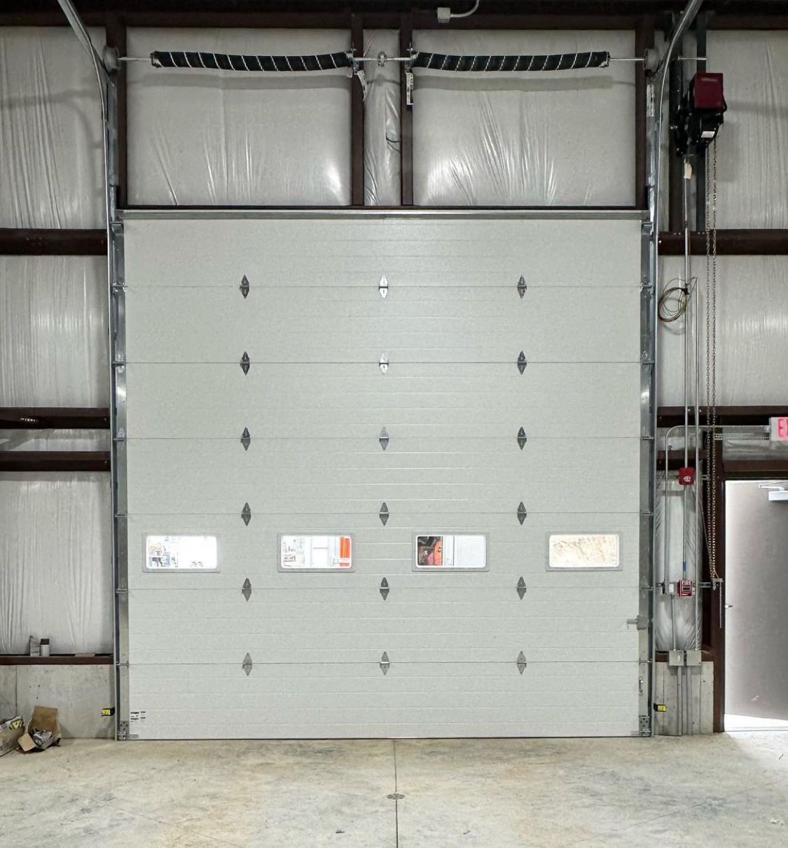 Large gray industrial overhead door inside a warehouse, with loading dock controls on the right.