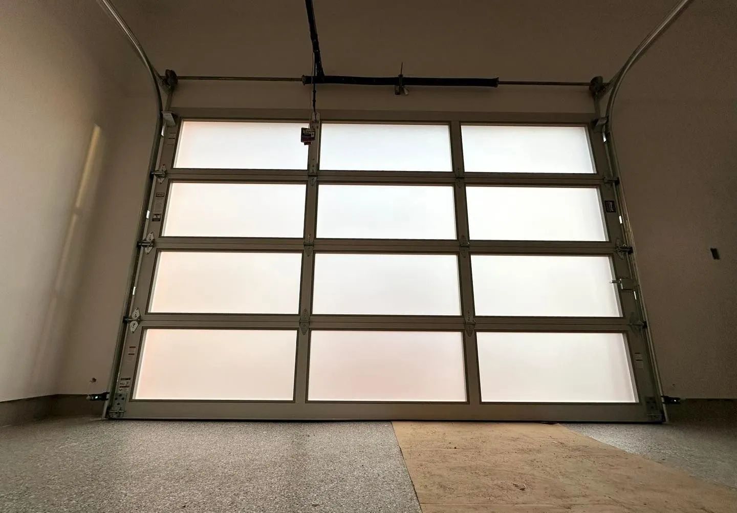 Closed frosted-glass garage door in a concrete garage interior