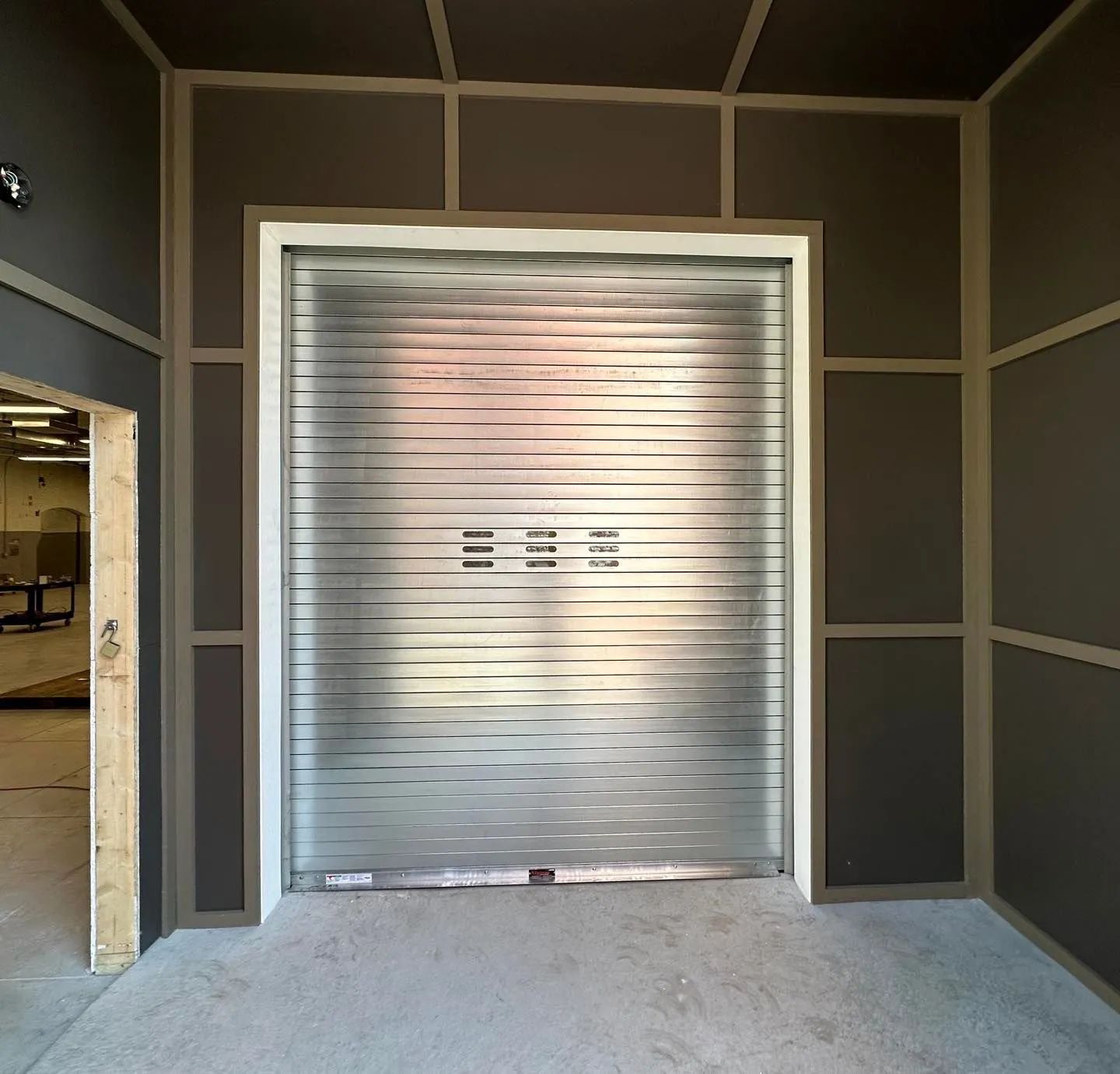 Interior view of a gray industrial roll-up door inside a framed doorway