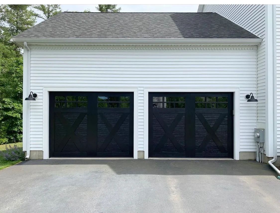 Two-car garage with white siding and black doors, viewed from the driveway