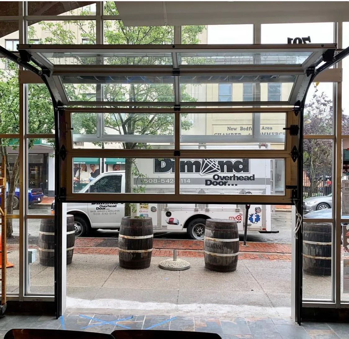 Glass entrance to a storefront with a black canopy and parked cars visible outside.