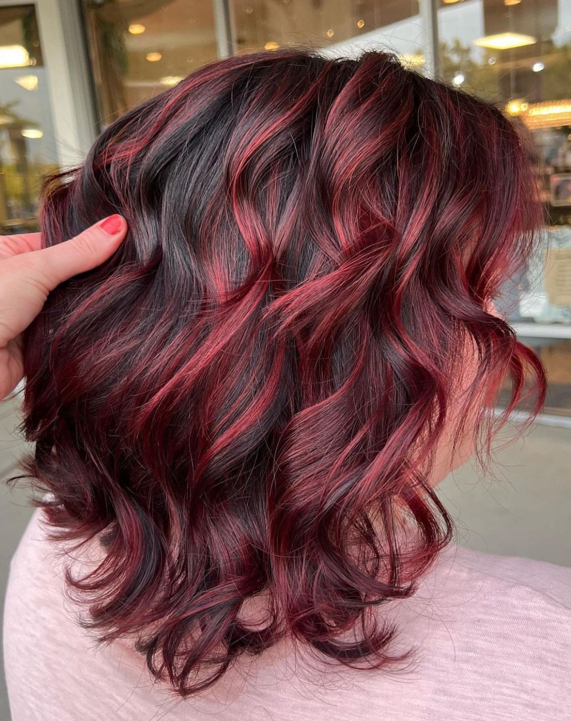 A woman with red hair is getting her hair dyed in a salon.
