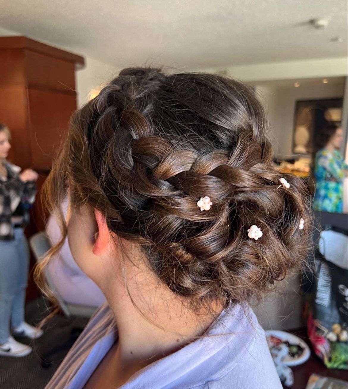 A woman is wearing a braided bun with flowers in her hair.