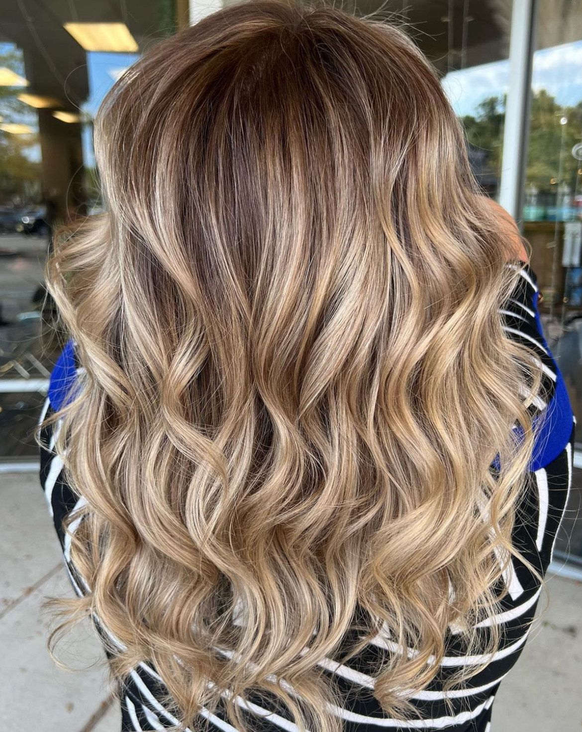 A woman with long wavy blonde hair is wearing a black and white striped shirt.