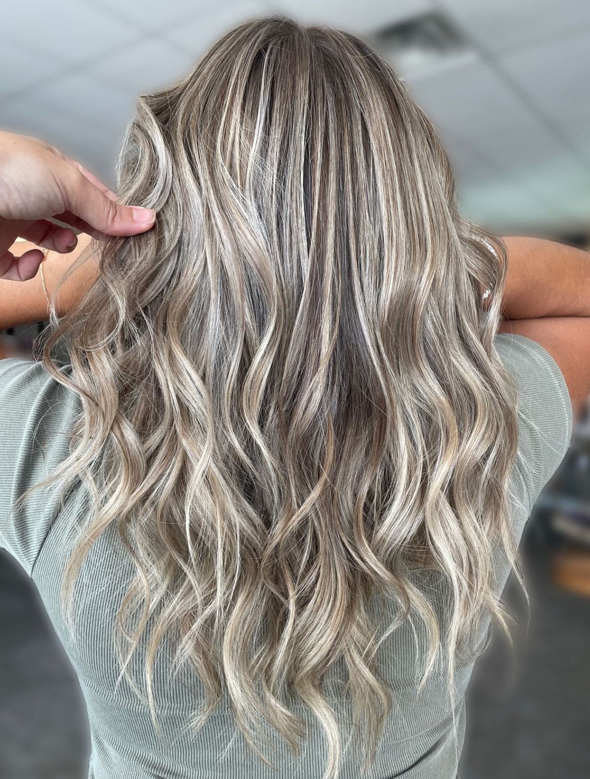 A woman with long blonde hair is getting her hair done by a hairdresser.
