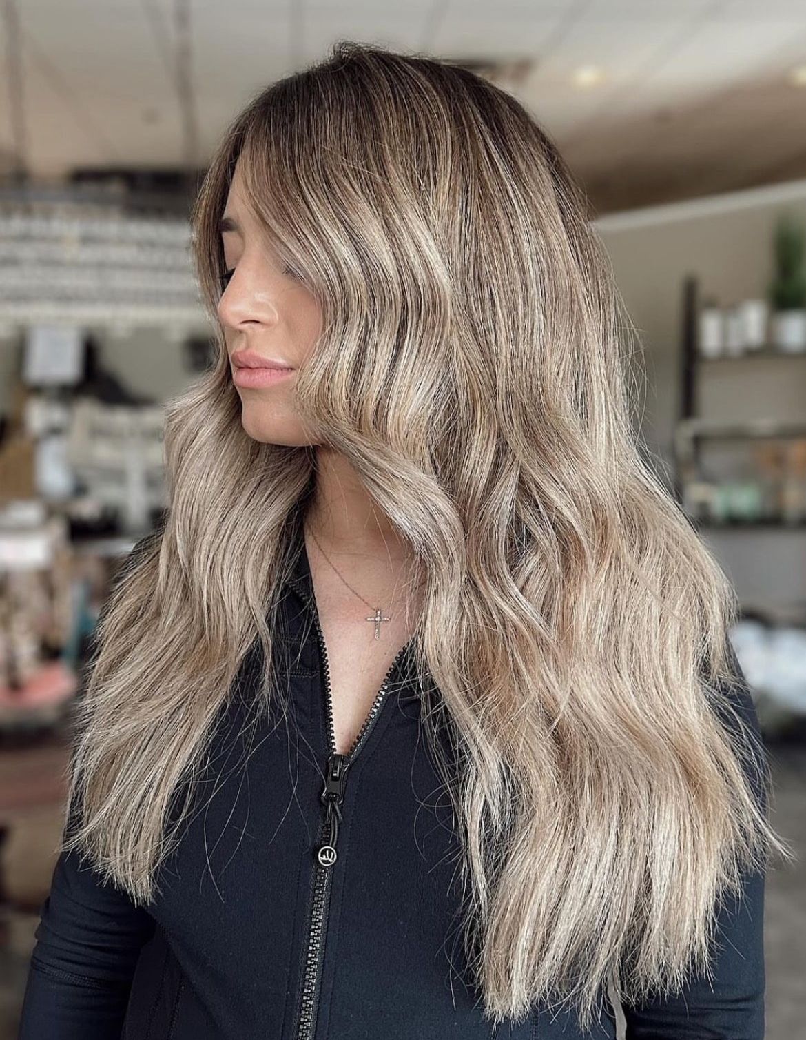 A woman with long blonde hair is wearing a black jacket.