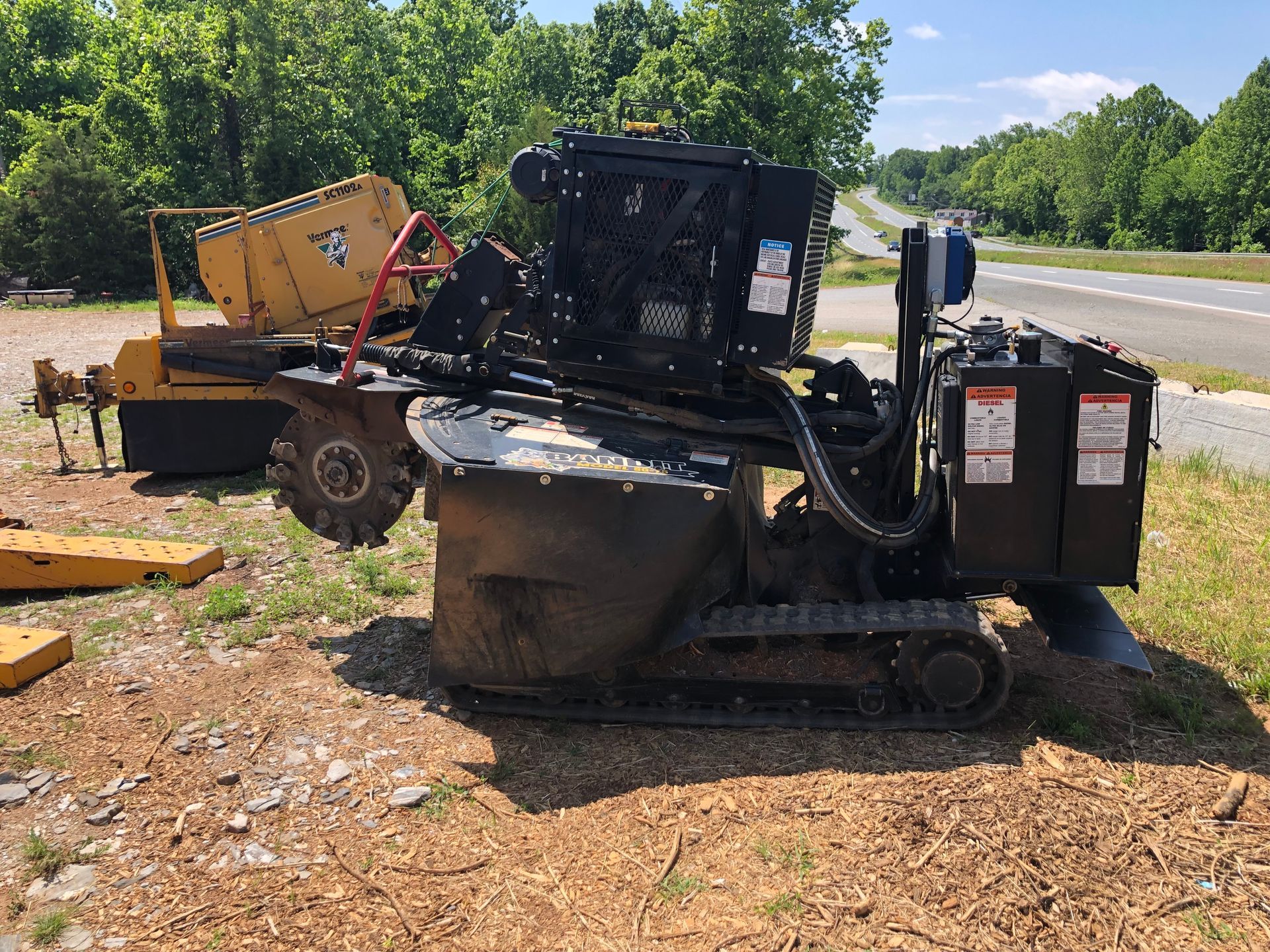 A stump grinder is parked in a grassy area next to a road.