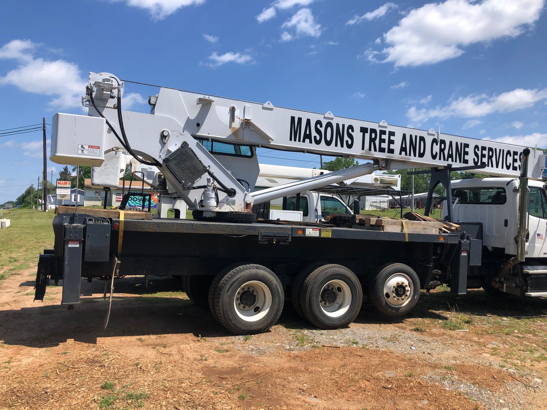 A truck with a crane attached to it is parked in a dirt field.