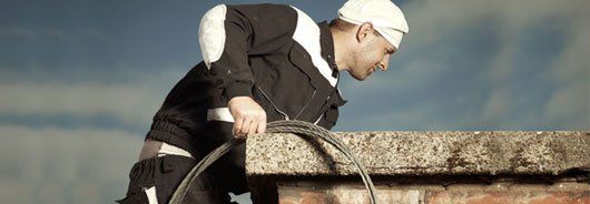 Man sweeping chimney from roof
