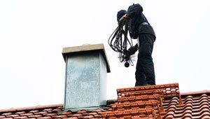 Man on roof with chimney sweeper