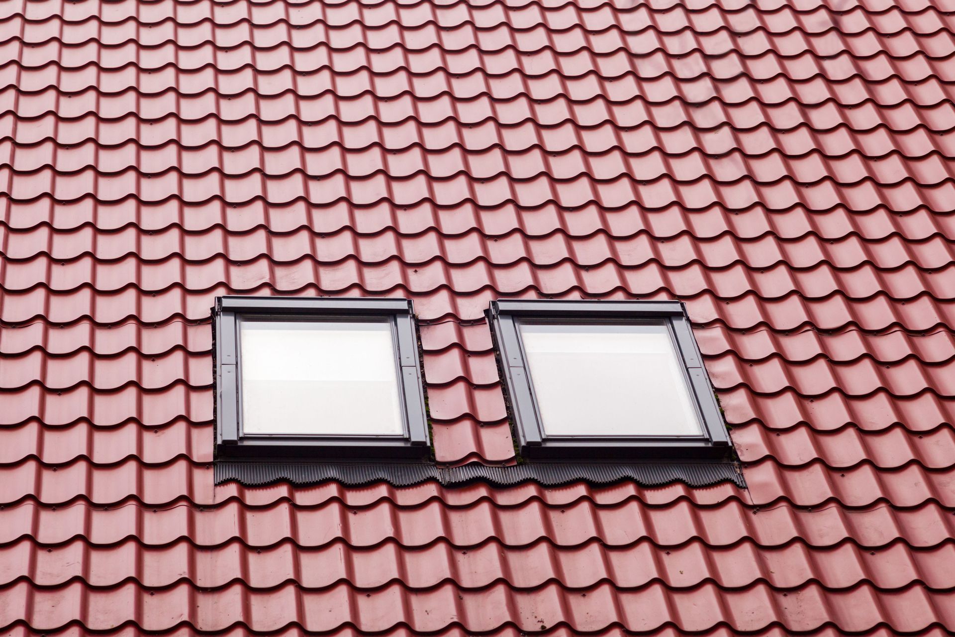 Red tile roof with two square skylights.