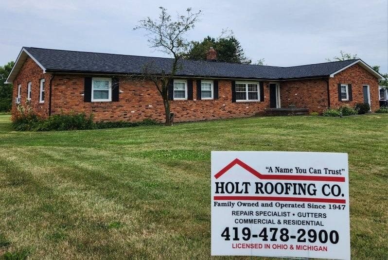 A brick ranch-style house with a new roof and a Holt Roofing sign in the yard.