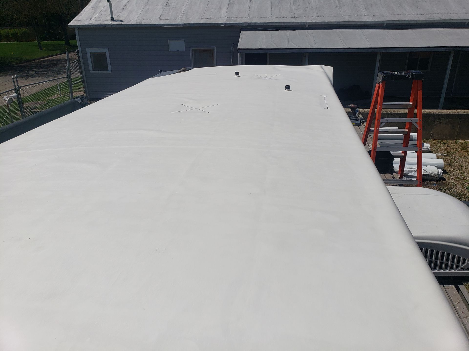 A white roof with a ladder sitting on top of it.