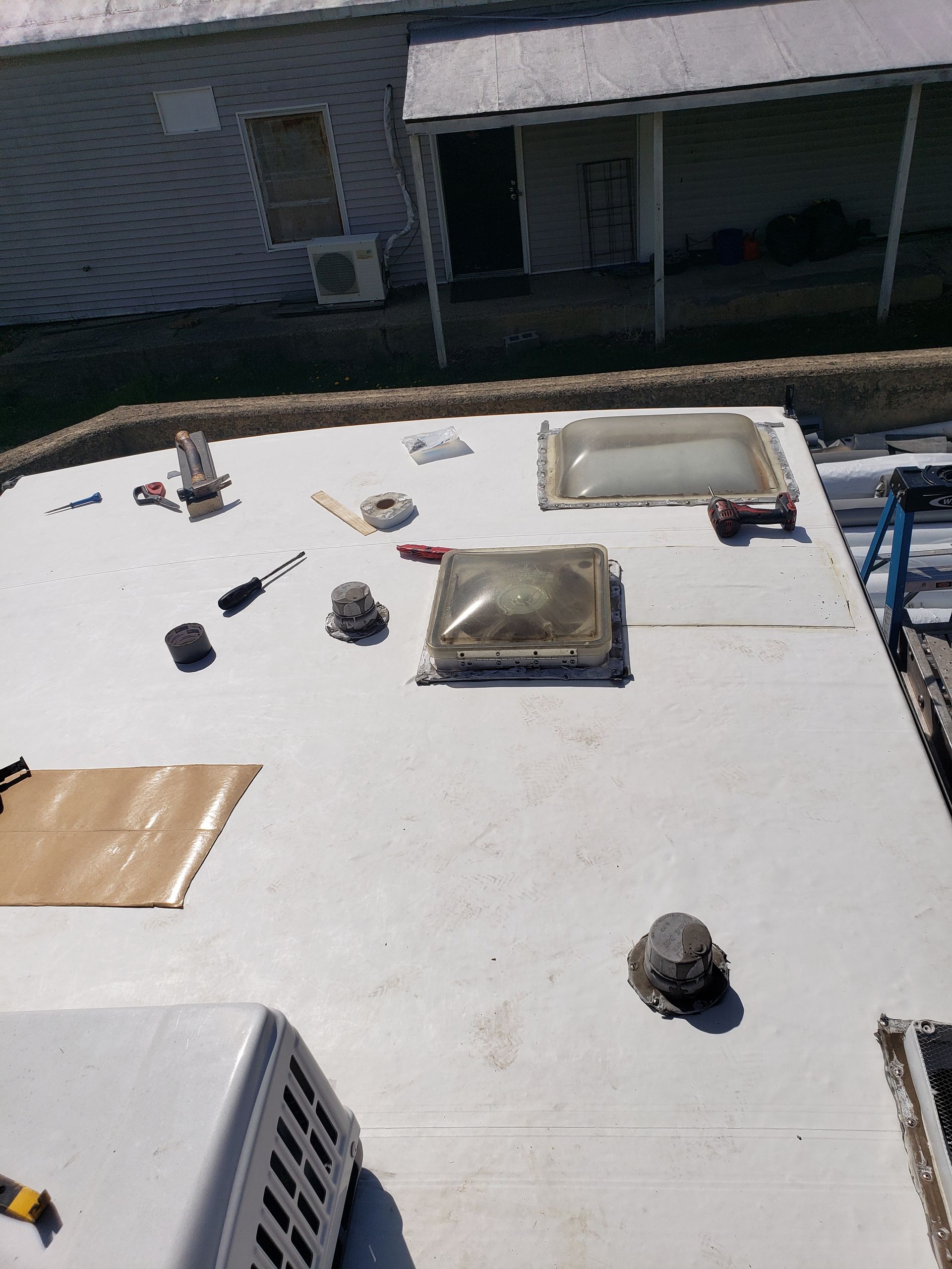 A white roof with two skylights on it is being repaired.