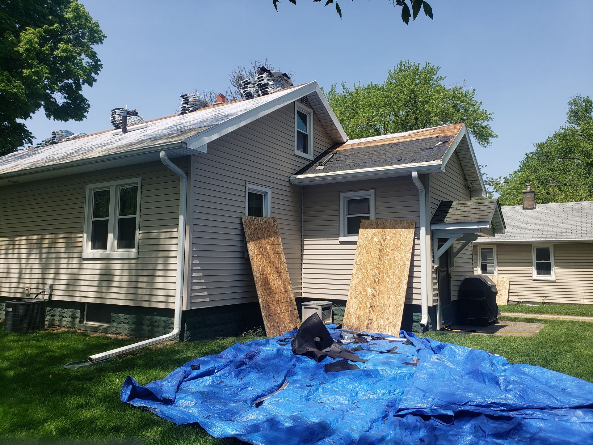 A house with a blue tarp in front of it is being remodeled.