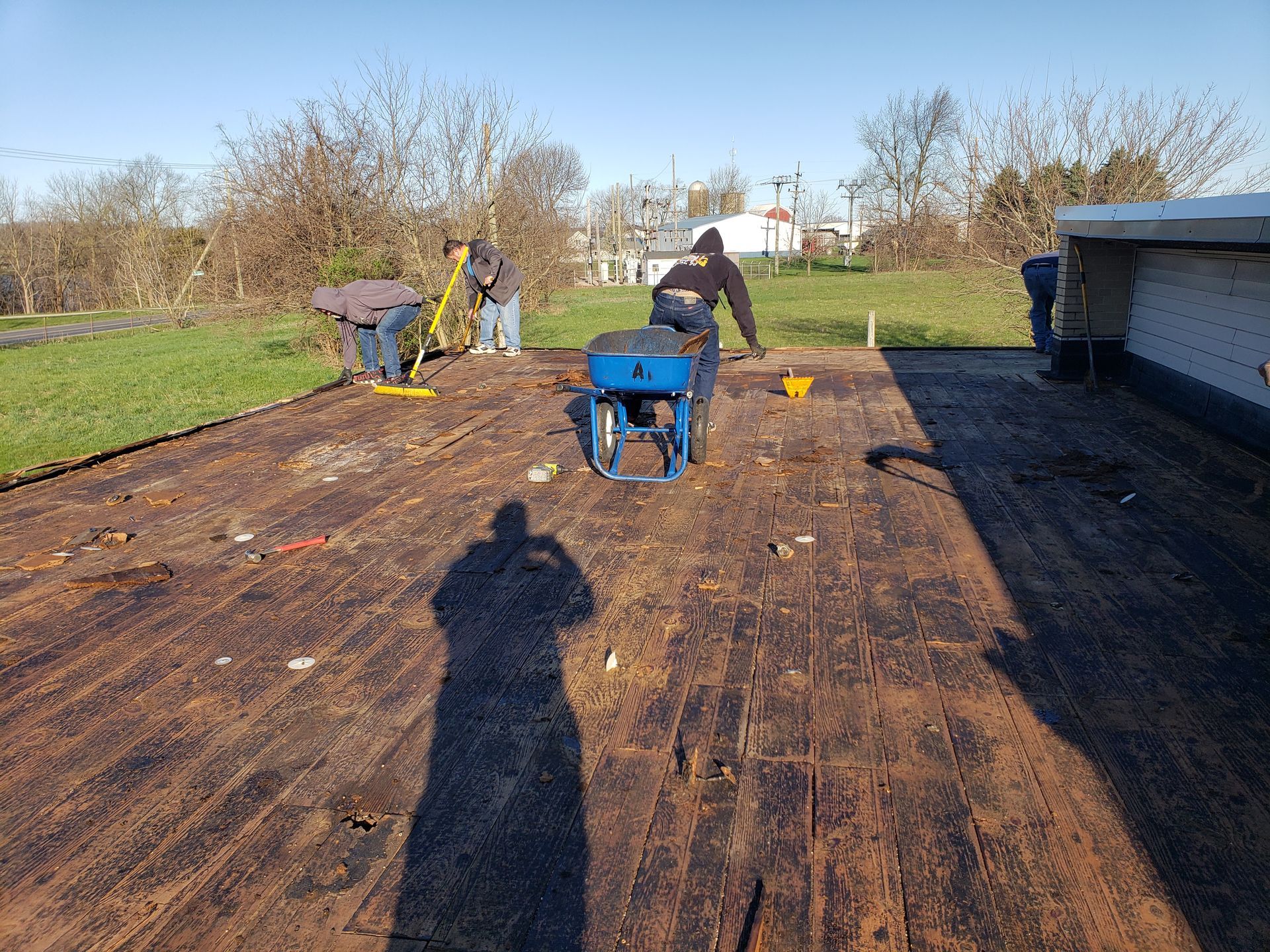 Two men are working on a roof with a wheelbarrow.