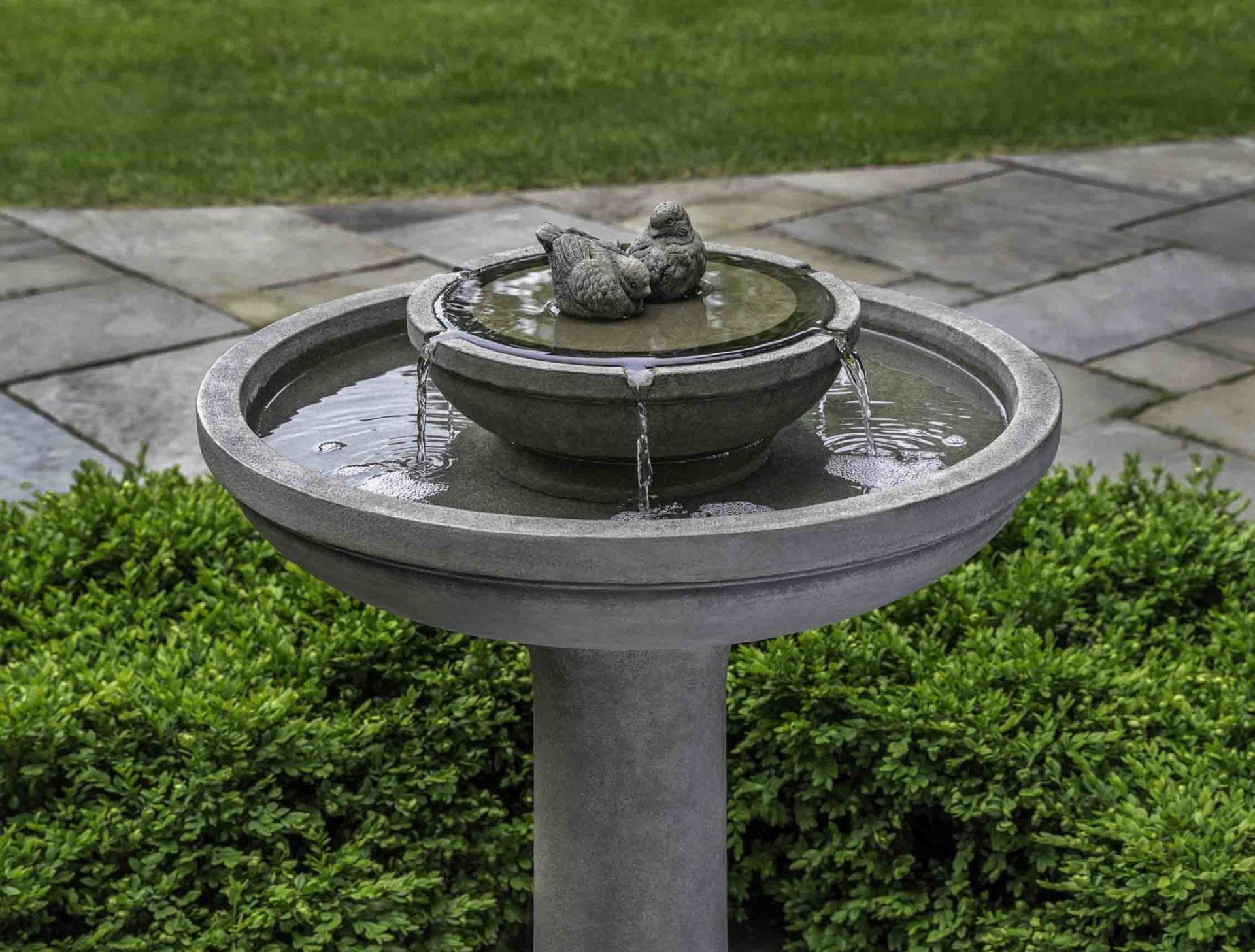 a bird bath with two birds in it is on a patio .