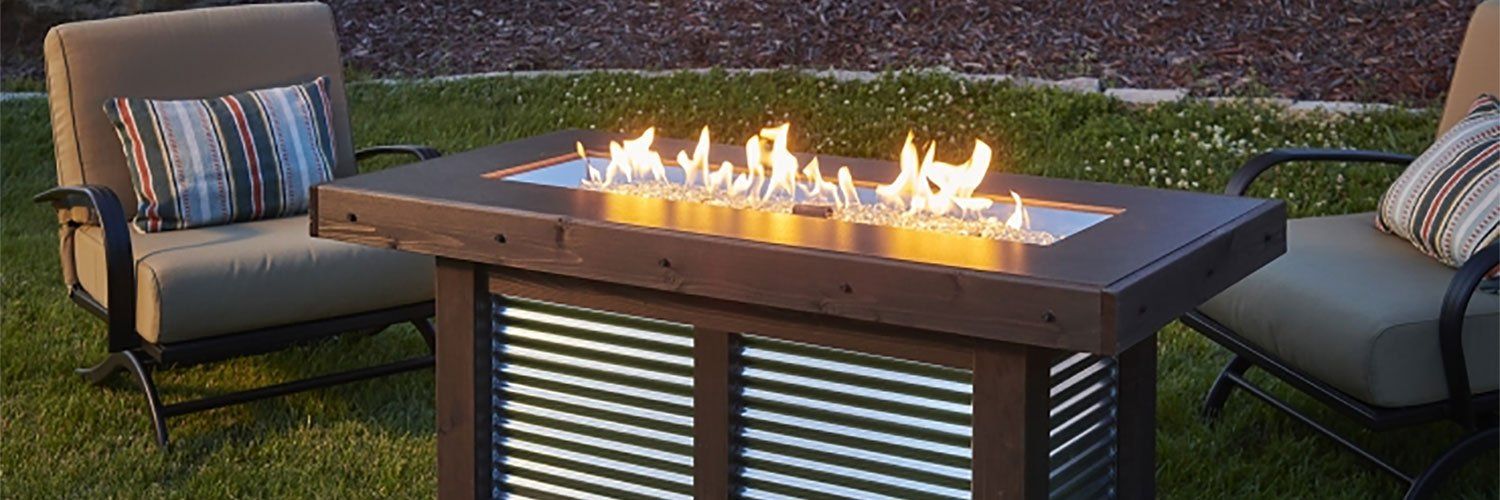 a fire pit is sitting in the middle of a lawn next to two chairs .