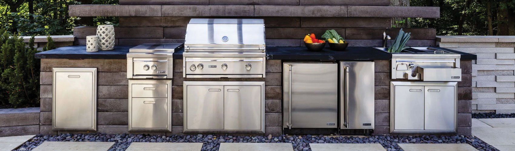 a stainless steel outdoor kitchen with a grill , sink , and refrigerator .