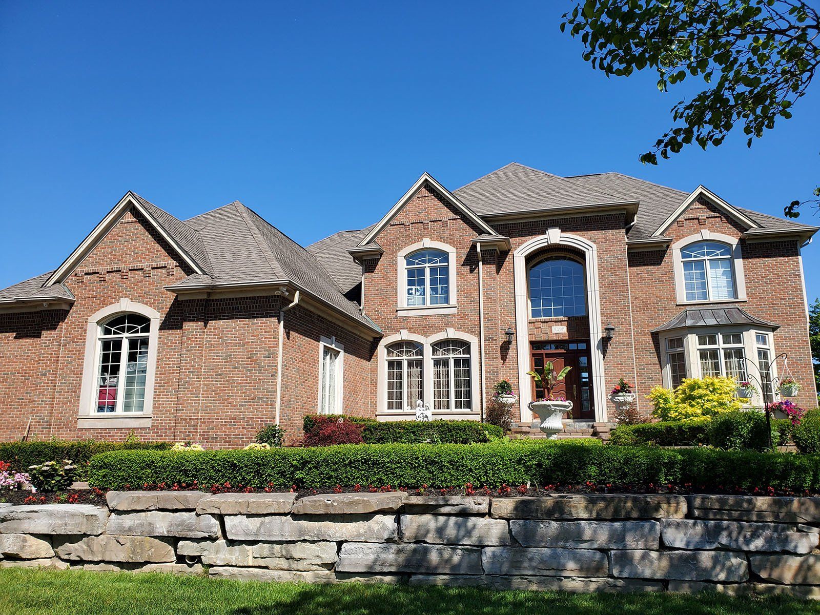 A large old brick house with a stone wall in front of it.
