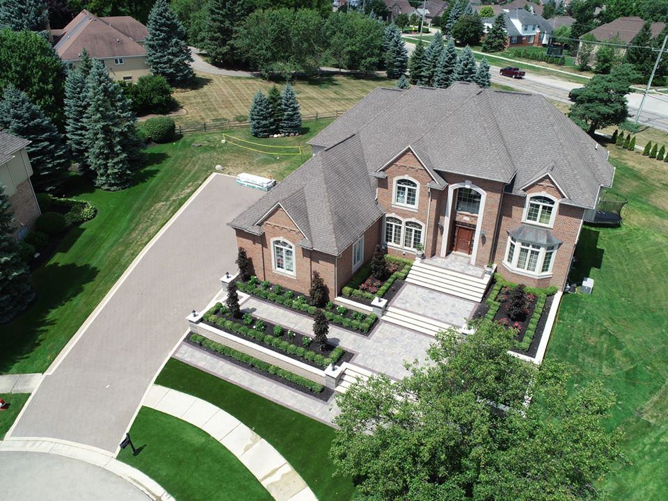 An aerial view of a large brick house in a residential area