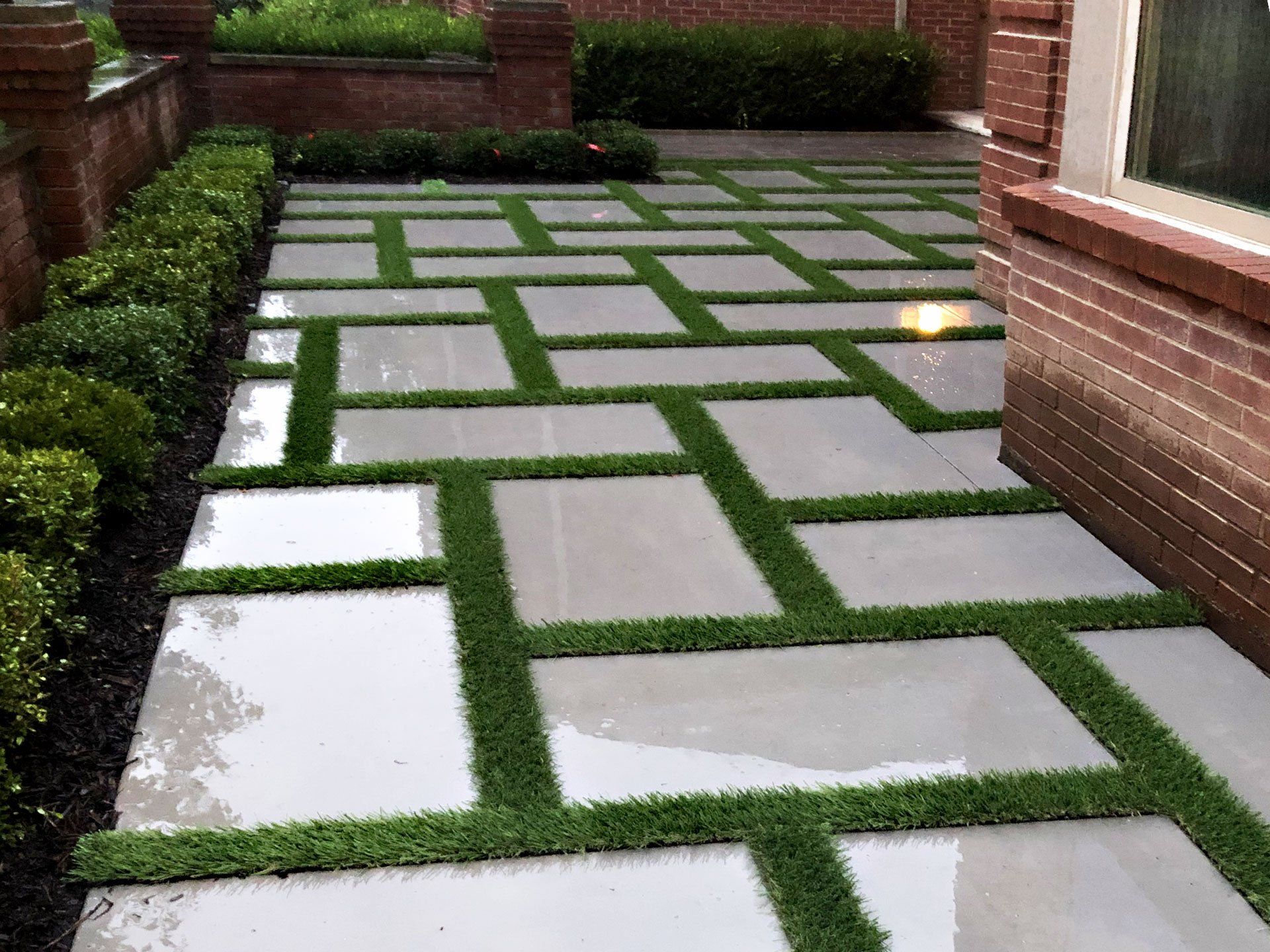 A brick walkway with grass between the tiles