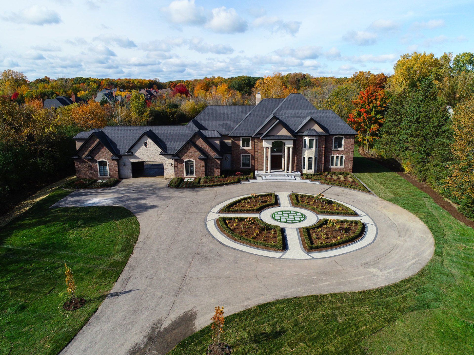 An aerial view of a large brick house with a driveway leading to it.